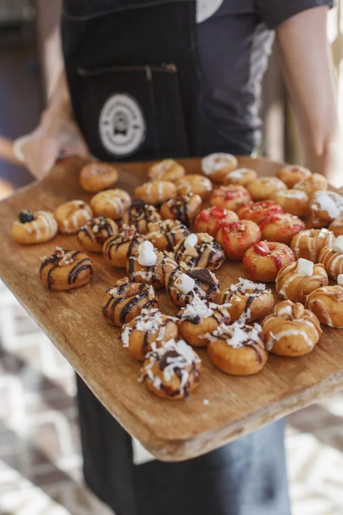The Dapper Doughnut server holding a board of mini donuts