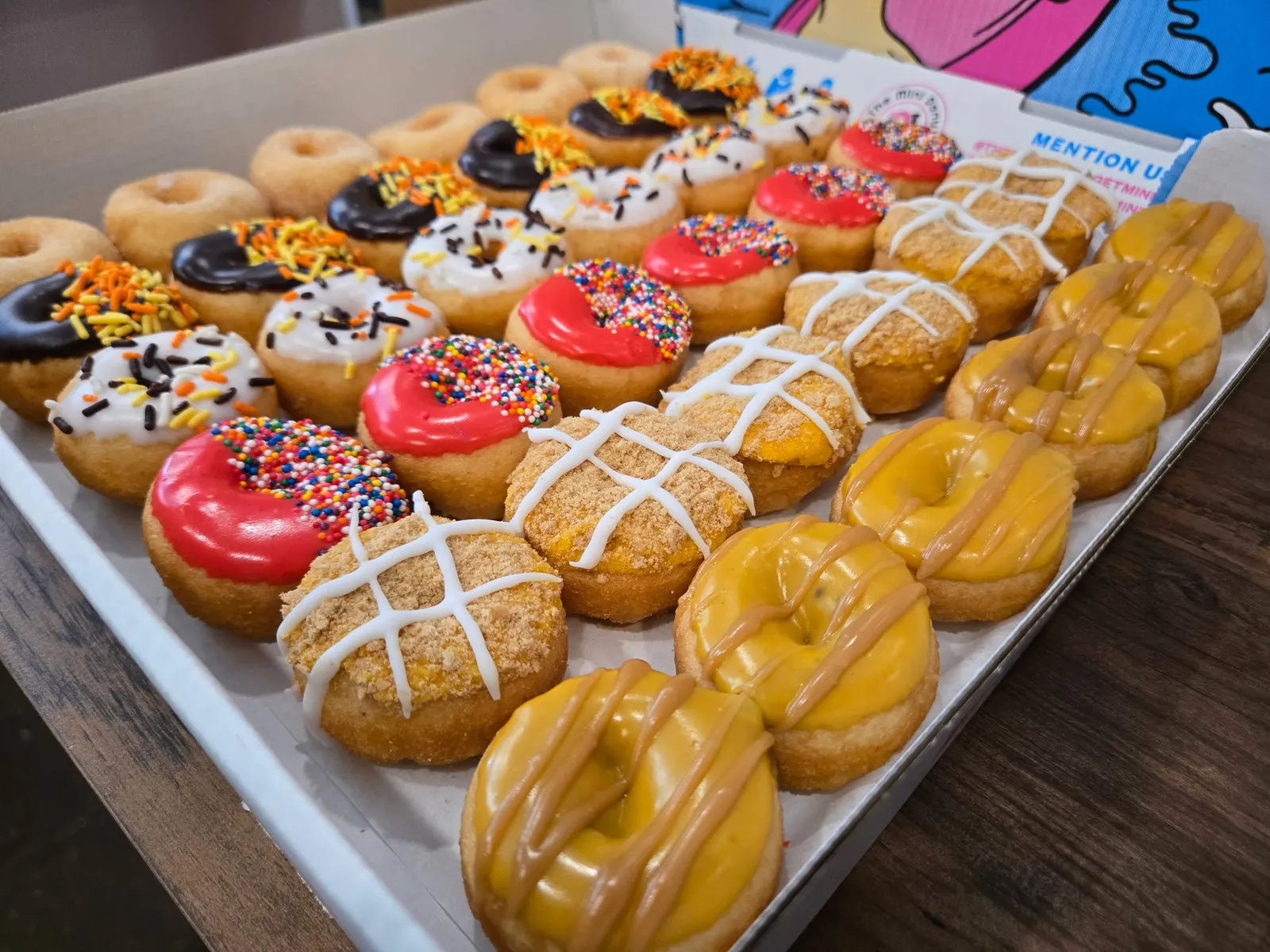 Open box of assorted frosted mini donuts