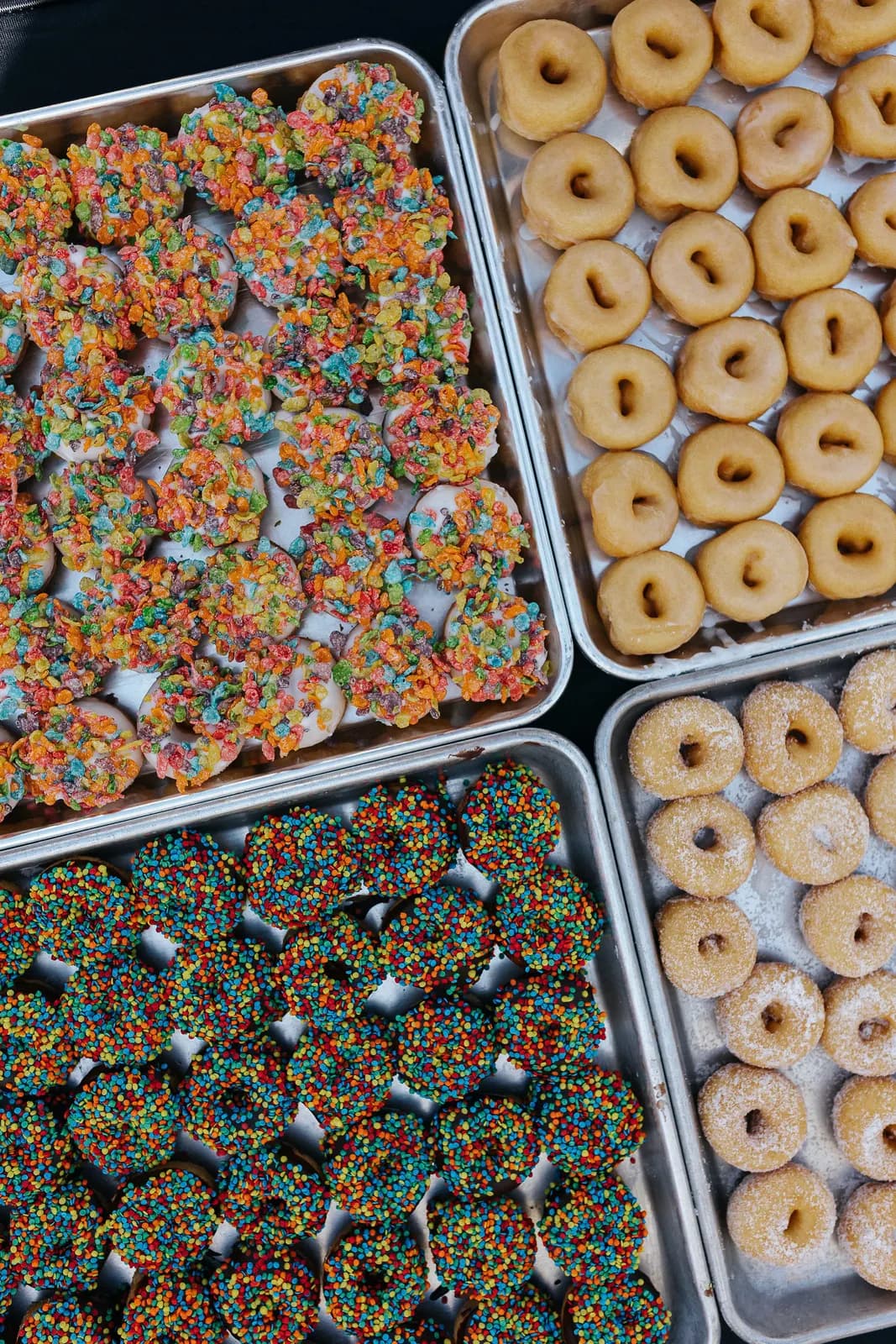 Variety of frosted mini donut trays in a flat lay
