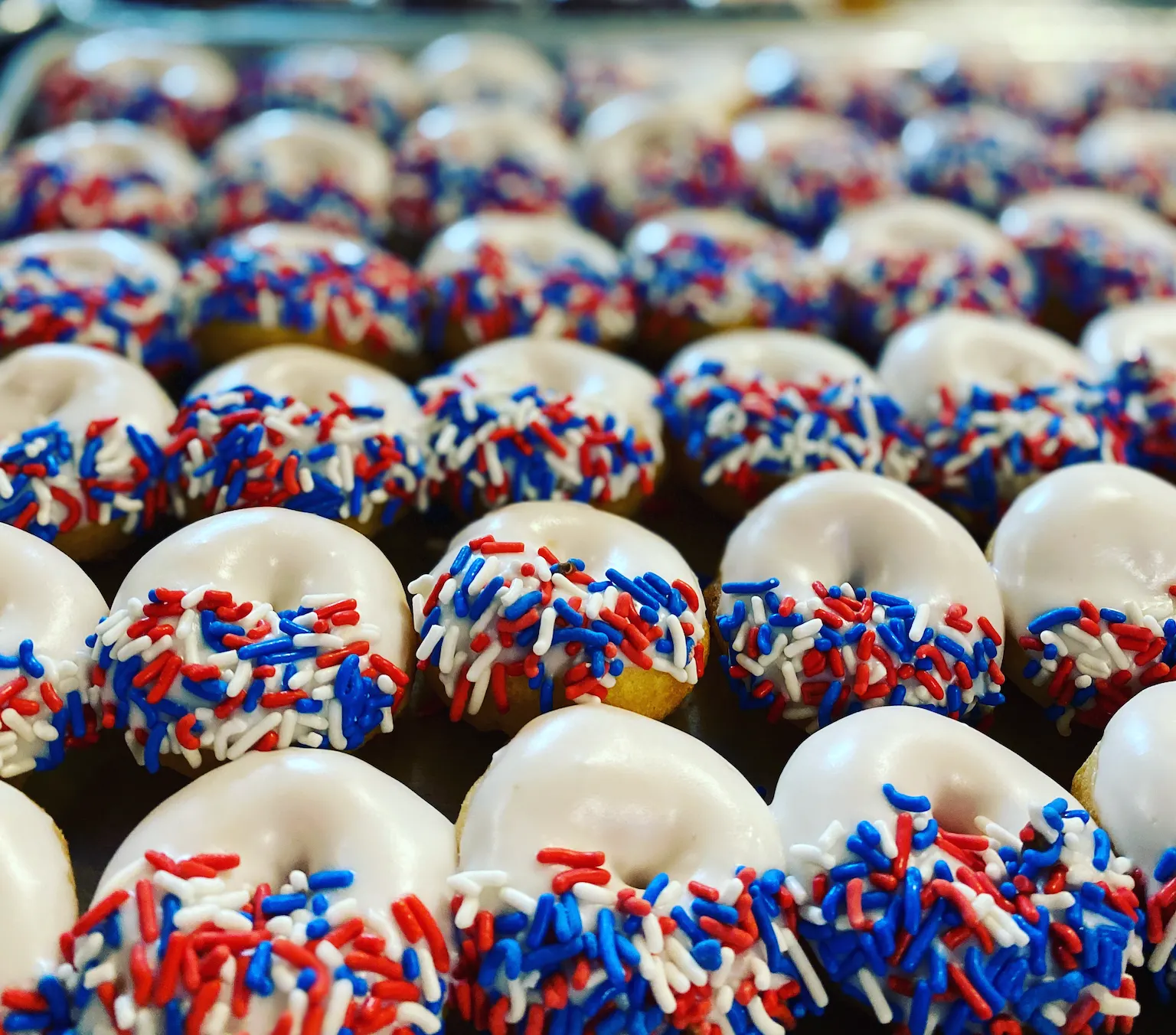Tray of white-frosted mini donuts with red white and blue sprinkles